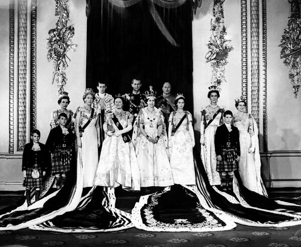Наряд для коронации был создан любимым модельером королевской семьи Норманом Хартнеллом. Платье из белого атласа было украшено вышитыми вручную цветами и растениями - национальными эмблемами Соединенного Королевства и стран Содружества, в том числе английской розой, шотландским чертополохом, ирландским клевером, канадским кленовым листом и другими символами. На фото - Принцесса Александра Кентская, принц Михаил Кентский, князь Кентский, принцесса Маргарет, герцог Глостерский, королева Елизавета II, герцог Эдинбургский, Королева Мать, молодой герцог Кентский , принцесса Королевская, герцогиня Глостерская, принц Уильям Глостер и принц Ричард Глостер в день коронации - Sputnik Грузия