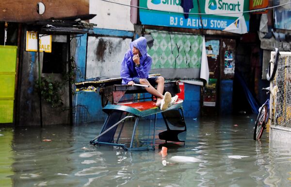 Человек на затопленной дождем улице, вызванным тропическим штормом Сон-Тинь в городе Кесон, Филиппины - Sputnik Грузия