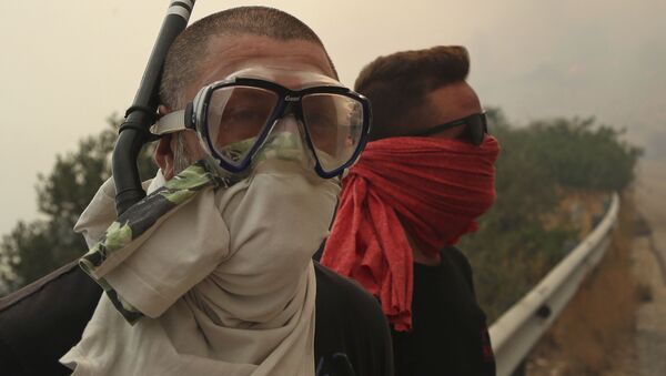 Люди закрывают лица, защищаясь от дыма лесных пожаров, бушующих в окрестностях Афин - Sputnik Грузия
