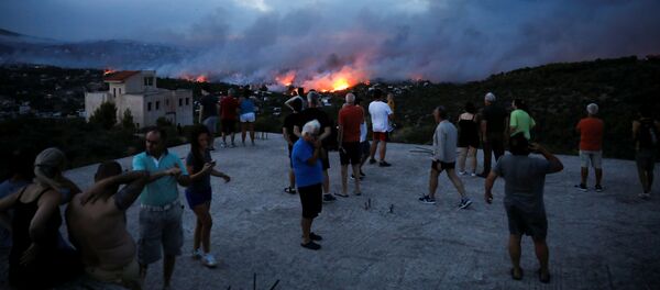 Люди наблюдают на распространением лесного пожара в греческом городе Рафина рядом с Афинами - Sputnik Грузия