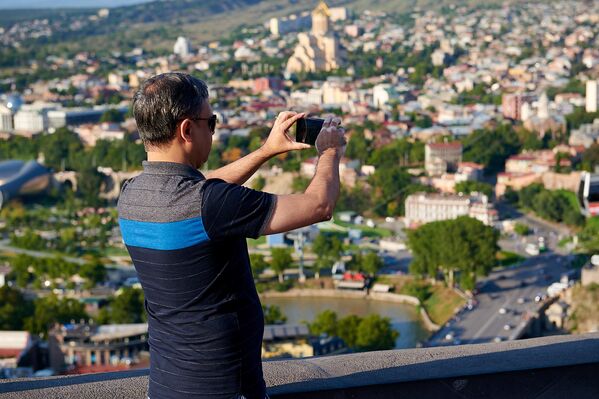 Далее следует Грузия. Турист фотографирует Тбилиси на смартфон - Sputnik Грузия