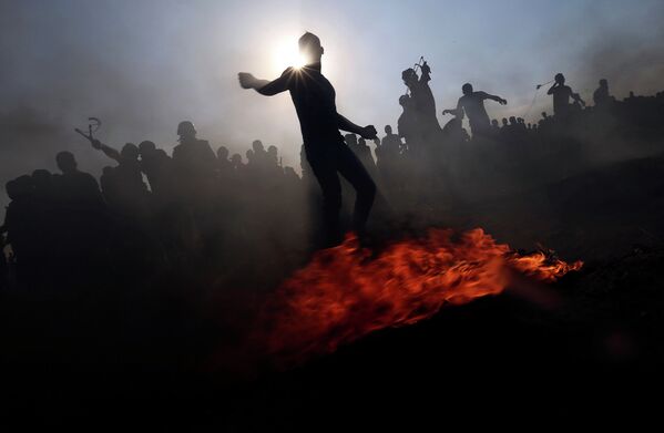 Палестинские демонстранты бросают камни в израильские войска во время акции протеста в южном Секторе Газа - Sputnik Грузия