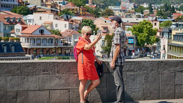 Пожилая пара туристов фотографируются на фоне Тбилиси - Sputnik Грузия