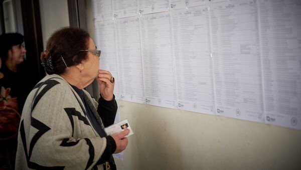 Жительница столицы Грузии на избирательном участке у списков с именами избирателей - Sputnik Грузия
