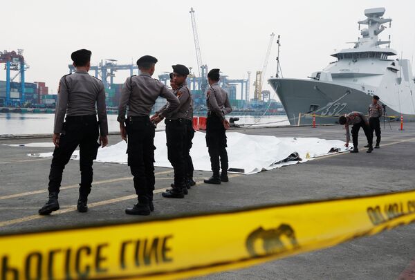 Вокруг чрезвычайной зоны в порту Джакарты, куда доставляют трагические находки с места крушения Боинга и где собрались родственники погибших, выставлено полицейское оцепление - Sputnik Грузия