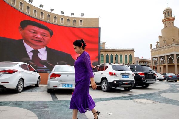 Женщина у гигантского экрана на главной городской площади в Кашгаре, Синьцзян-Уйгурский автономный район, Китай - Sputnik Грузия