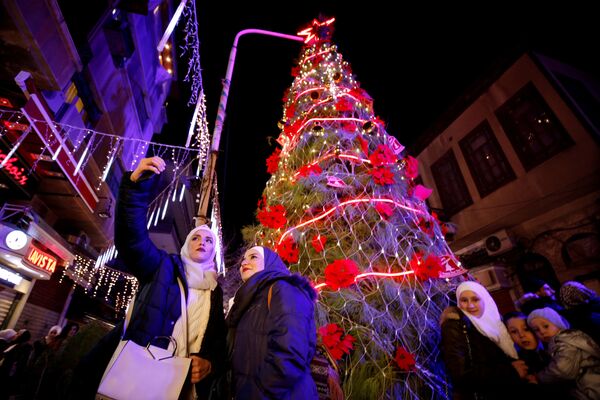 Люди делают селфи перед Рождественской елкой в районе Касаа в  Дамаске - Sputnik Грузия