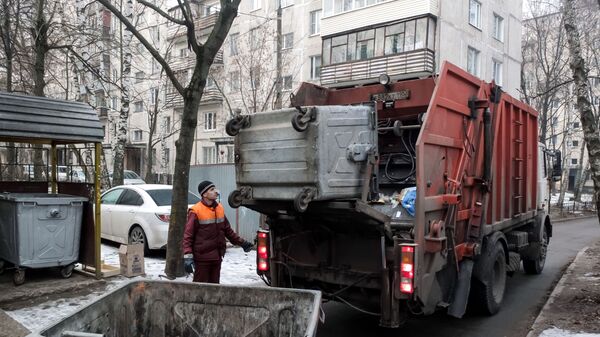 Сотрудник коммунальных служб выгружает мусор из контейнера в мусоровоз - Sputnik Грузия