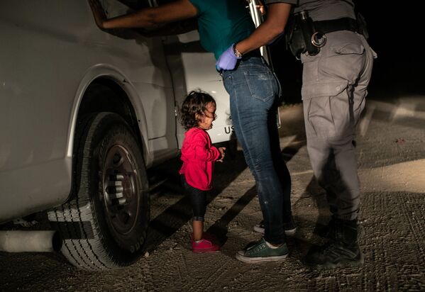 Плачущая девочка на границе Джона Мура изображает маленькую девочку из Гондураса, чью мать обыскивают американские пограничники в Техасе - Sputnik Грузия