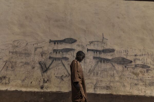Снимок Марко Гуалаззини Мальчик из Алмаджири изображает ребенка в городе Бол в Чаде у стены, разрисованной изображениями гранатометов. В этом районе активна группировка Боко Харам, пополняющая здесь ряды своих бойцов - Sputnik Грузия