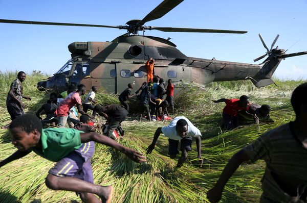 Местные жители разбегаются от вертолета Южно-Африканских национальных сил обороны, который привез продовольственную помощь в деревню, пострадавшую от циклона, Мозамбик - Sputnik Грузия