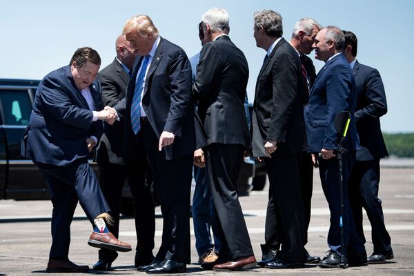 Вице-губернатор штата Луизиана Билли Нунгессер показывает президенту США Дональду Трампу носки с его изображением в аэропорте Лейк-Чарлз - Sputnik Грузия