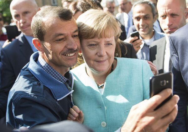 Беженец делает селфи с канцлером Германии Ангелой Меркель во время ее визита в центр для новоприбывших беженцев в Берлине - Sputnik Грузия