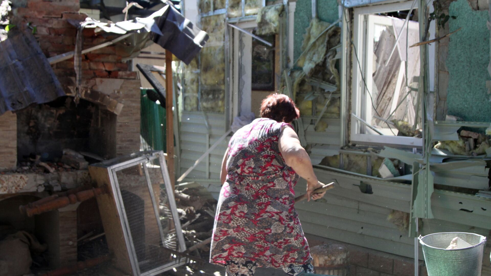 Женщина убирает мусор во дворе жилого дома в Донецке, пострадавшего в результате обстрела - Sputnik Грузия, 1920, 03.06.2022