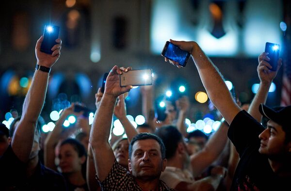 Также в знак солидарности участники акции зажигали экраны смартфонов и поднимали их над головой - Sputnik Грузия