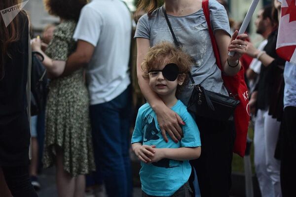 Мальчик с повязкой на глазу - такая повязка стала одним из символов протеста против силового разгона митинга в центре Тбилиси в ночь на 21 июня - Sputnik Грузия