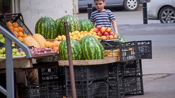 Мальчик у прилавка уличного торговца, продающего фрукты, овощи, арбузы и дыни - Sputnik Грузия