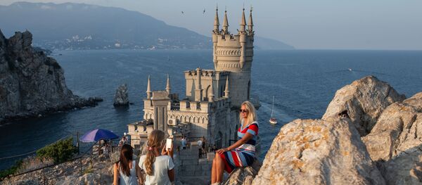 Отдыхающие фотографируются возле замка Ласточкино гнездо на береговой скале в поселке Гаспра в Крыму - Sputnik Грузия