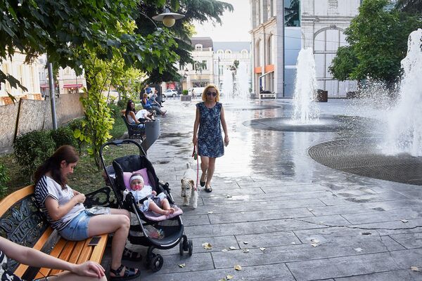 Тем временем взрослые, среди которых немало родителей с маленькими детьми, сидят на скамейках вдоль фонтанов - тут тоже намного прохладнее, чем на раскаленных августовским солнцем улицах - Sputnik Грузия