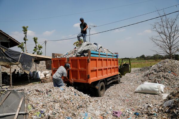 Мусорщик готовится выгрузить отходы из грузовика, тем самым засорив окружающую деревню с населением в 3600 человек - Sputnik Грузия