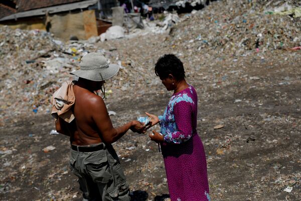 Местная жительница получает деньги после выгрузки мусора в ее родной деревне Бангун. Хотя это и прибыльно, груды мусора представляют угрозу для здоровья жителей деревни, говорят экологи - Sputnik Грузия