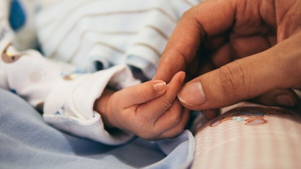 Новорожденного малыша держат за руку - Sputnik Грузия