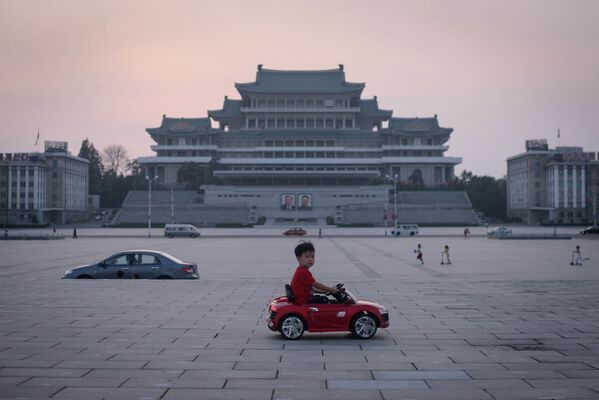 Мальчик на игрушечной машине на площади Ким Ир Сена в Пхеньяне, Северная Корея - Sputnik Грузия