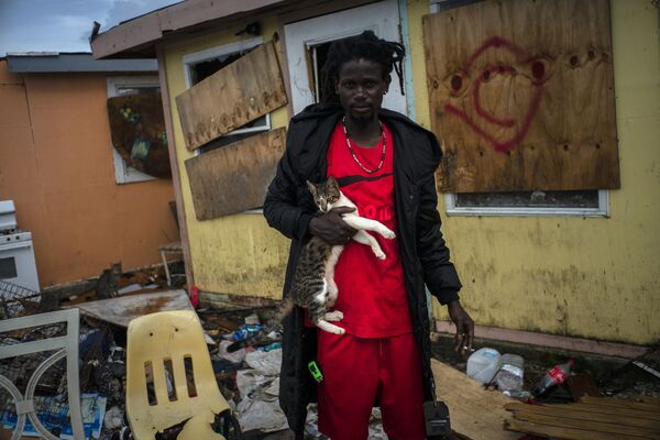 Владимир Саффорд, иммигрант из Гаити, забирает своего кота из разрушенного дома а Абако - Sputnik Грузия
