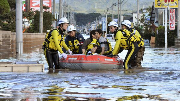 Местные жители сидят в лодке, когда их спасают из затопленного жилого района после тайфуна в Японии - Sputnik Грузия