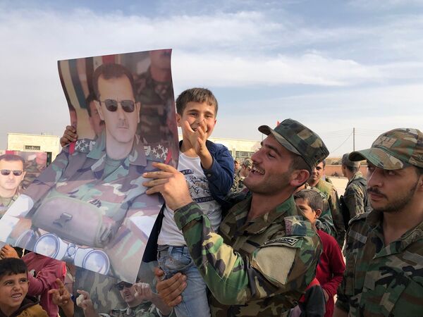 Дети и военнослужащие с плакатами с портретом президента Сирии Башара Асада в освобожденном сирийской правительственной армией городе Манбидж в Сирии - Sputnik Грузия