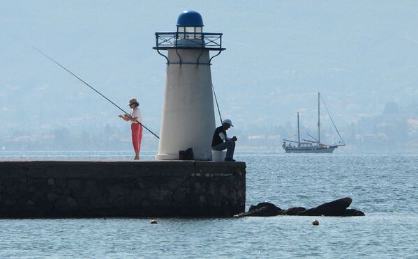 Отдыхающие ловят рыбу возле маяка в заливе Нотиос-Эввоикос Эгейского моря - Sputnik Грузия