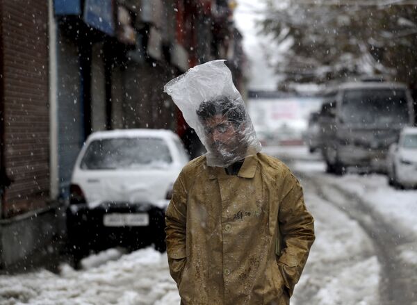 Мужчина прикрывает голову полиэтиленовым пакетом во время снегопада в Сринагаре, Кашмир - Sputnik Грузия