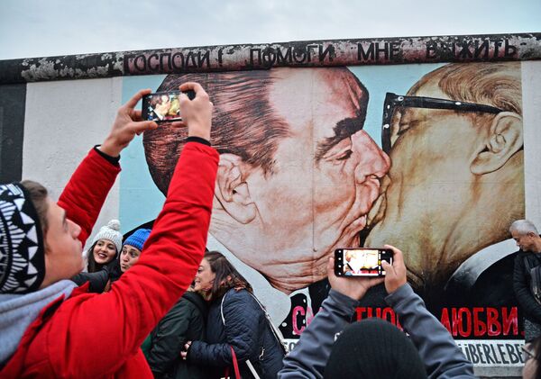 Люди у фрагмента Берлинской стены на Мюленштрассе с произведением Дмитрия Врубеля Господи! Помоги мне выжить среди этой смертной любви или Братский поцелуй (поцелуй Брежнева и Хонеккера) - Sputnik Грузия