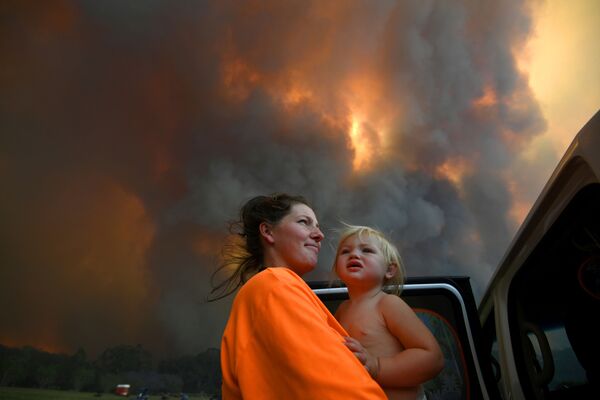 Женщина в ребенком на руках в дыму природных пожаров в Австралии - Sputnik Грузия