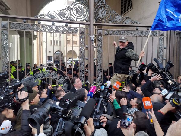 Тем временем бывший мэр Тбилиси Гиги Угулава собрал единомышленников и обошел по периметру здание парламента, заперев снаружи все ворота на большие амбарные замки

 - Sputnik Грузия