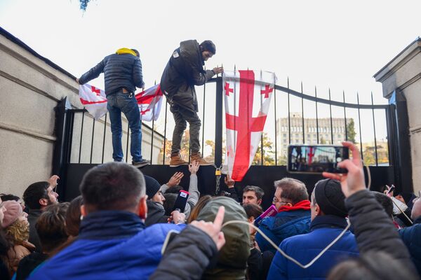 На фото - протестующие пытаются повесить замки на железные ворота одного из зданий МВД Грузии, которое находится на улице Читадзе. Это происходило днем 18 ноября - Sputnik Грузия