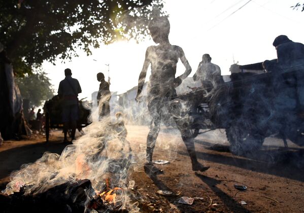 Люди проходят мимо горящего мусора в Калькутте, Индия - Sputnik Грузия