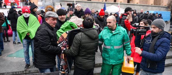 Протестующие перемещают соратника в машину скорой. 26 ноября. Акция протеста у здания парламента Грузии продолжается - Sputnik Грузия
