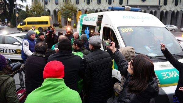 Протестующие перемещают соратника в машину скорой. 26 ноября. Акция протеста у здания парламента Грузии продолжается - Sputnik Грузия