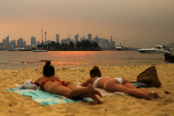 Девушки, загорающие на пляже на фоне дымки от лесных пожаров в Австралии - Sputnik Грузия