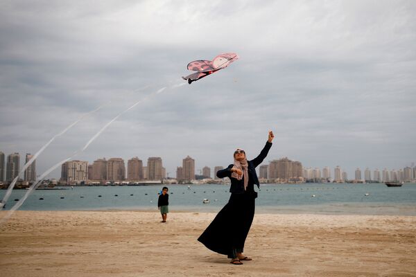 Женщина в мусульманской одежде с воздушным змеем на пляже в Дохе, Катар. В этой стране регулярно проводятся международные фестивали воздушных змеев, собирающие сотни участников - Sputnik Грузия
