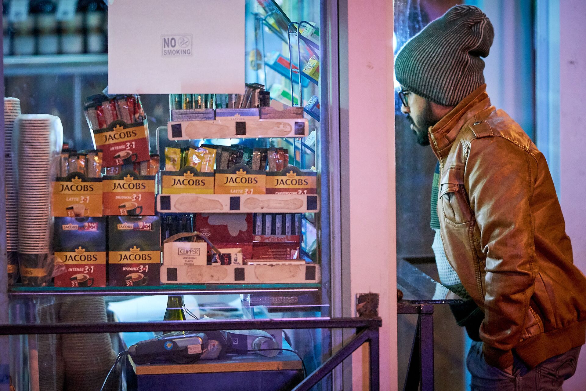 Мужчина в шапке и кожаной куртке покупает в уличном киоске кофе и сигареты - Sputnik საქართველო, 1920, 08.05.2022