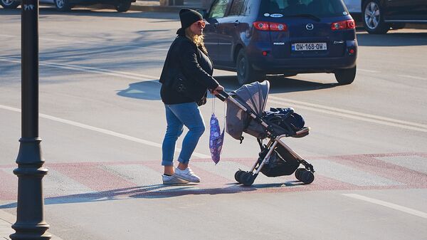 Женщина с ребенком в коляске переходит дорогу по зебре - Sputnik Грузия