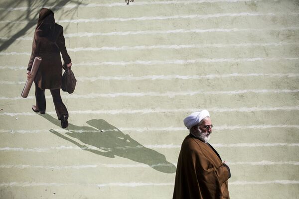 Иранский священнослужитель проходит мимо фрески с изображением женщины в центре Тегерана - Sputnik Грузия