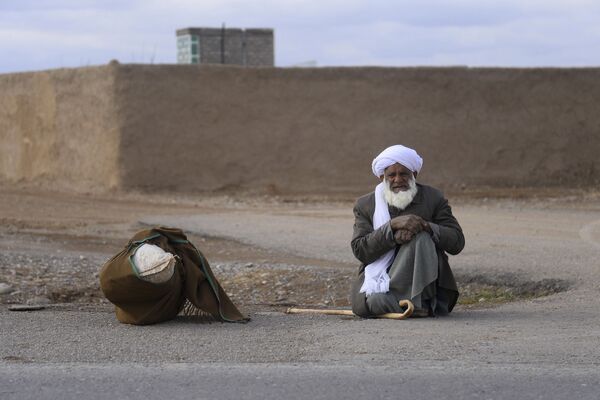 Пожилой мужчина сидит на обочине дороги на окраине Герата в Афганистане - Sputnik Грузия