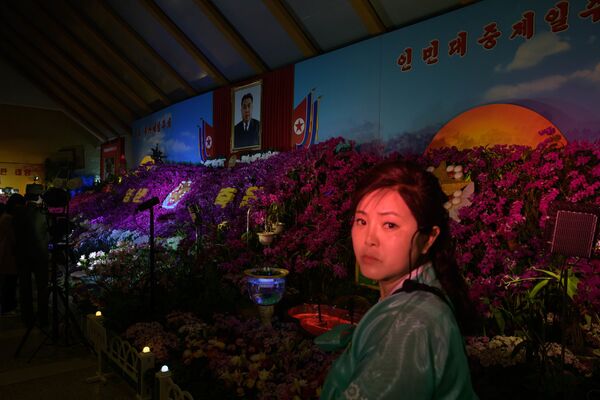 Посетительница под портретом Ким Ир Сена на цветочной выставке в рамках празднования Дня солнца в Пхеньяне - Sputnik Грузия