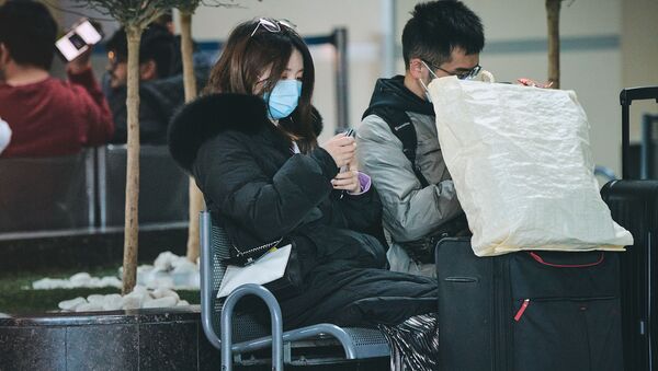 Турист с Востока в маске в тбилисском аэропорту читает сообщения в соцсети на смартфоне - Sputnik Грузия