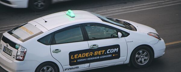 Автомобиль Toyota Prius - белое такси едет в центре города - Sputnik Грузия