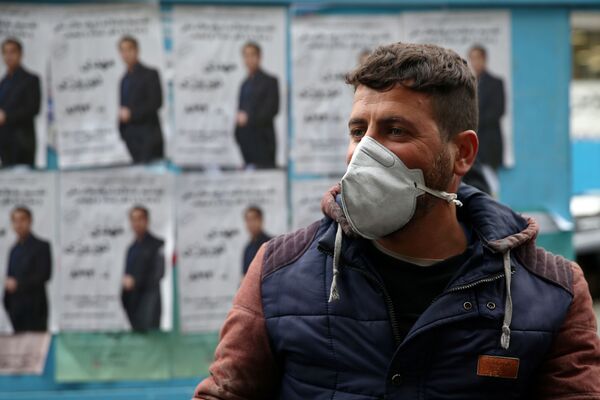В Иране тоже зафиксировано около 100 случаев коронавируса. В таких условиях в стране состоялись парламентские выборы. На снимке - житель Тегерана на фоне избирательных плакатов - Sputnik Грузия