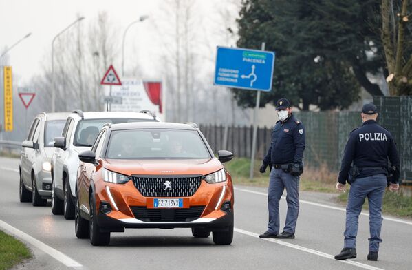 Сотрудники итальянской полиции тоже одели средства защиты. На снимке - полицейские в масках предупреждают водителей о закрытии дороги между Кодоньо и Казальпустерленго. Ограничение на движение машин было введено из-за вспышки коронавируса в северной Италии - Sputnik Грузия